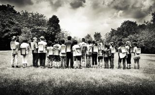 Black and white photo of children standing in a line with backs to the camera