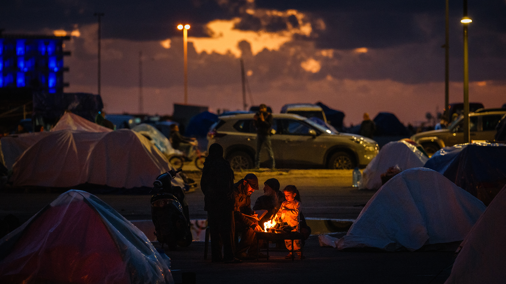 A family warms up by the fire at a camp for displaced people on the Beirut seafront amid ongoing hostilities between Israel and Hezbollah