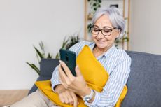 Happy woman laughing while watching media content on smartphone app at home. 