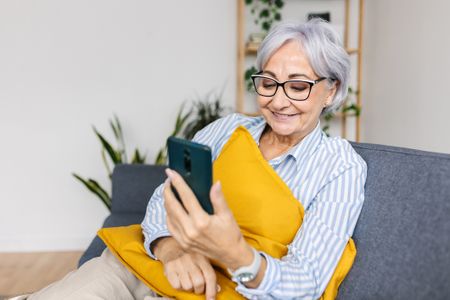 Happy woman laughing while watching media content on smartphone app at home. 