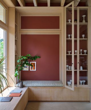 dark red wall in modern wood shelving unit and seating bench