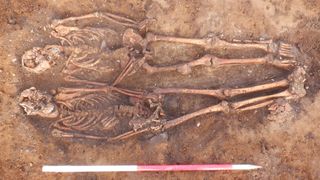 Two human skeletons buried side by side in a medieval cemetery.
