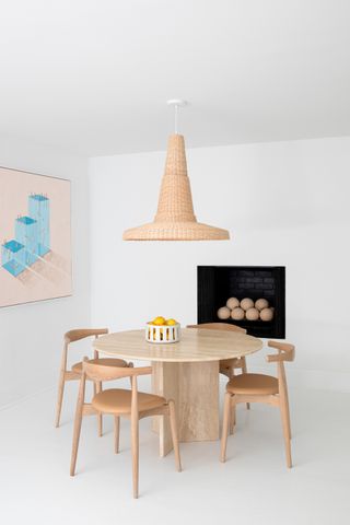 dining room color drenched in white with rattan pendant light, stone table and blue artwork