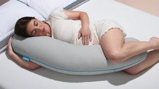 A pregnant woman on a bed with the Simba Cooling Body Pillow
