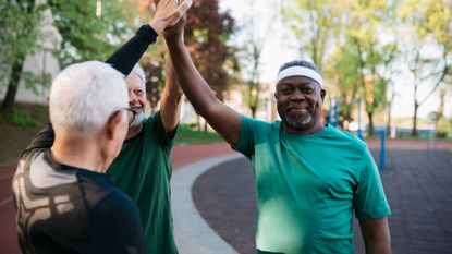 Multiracial group of elderly men giving a high five to each other after workout in exercise court.