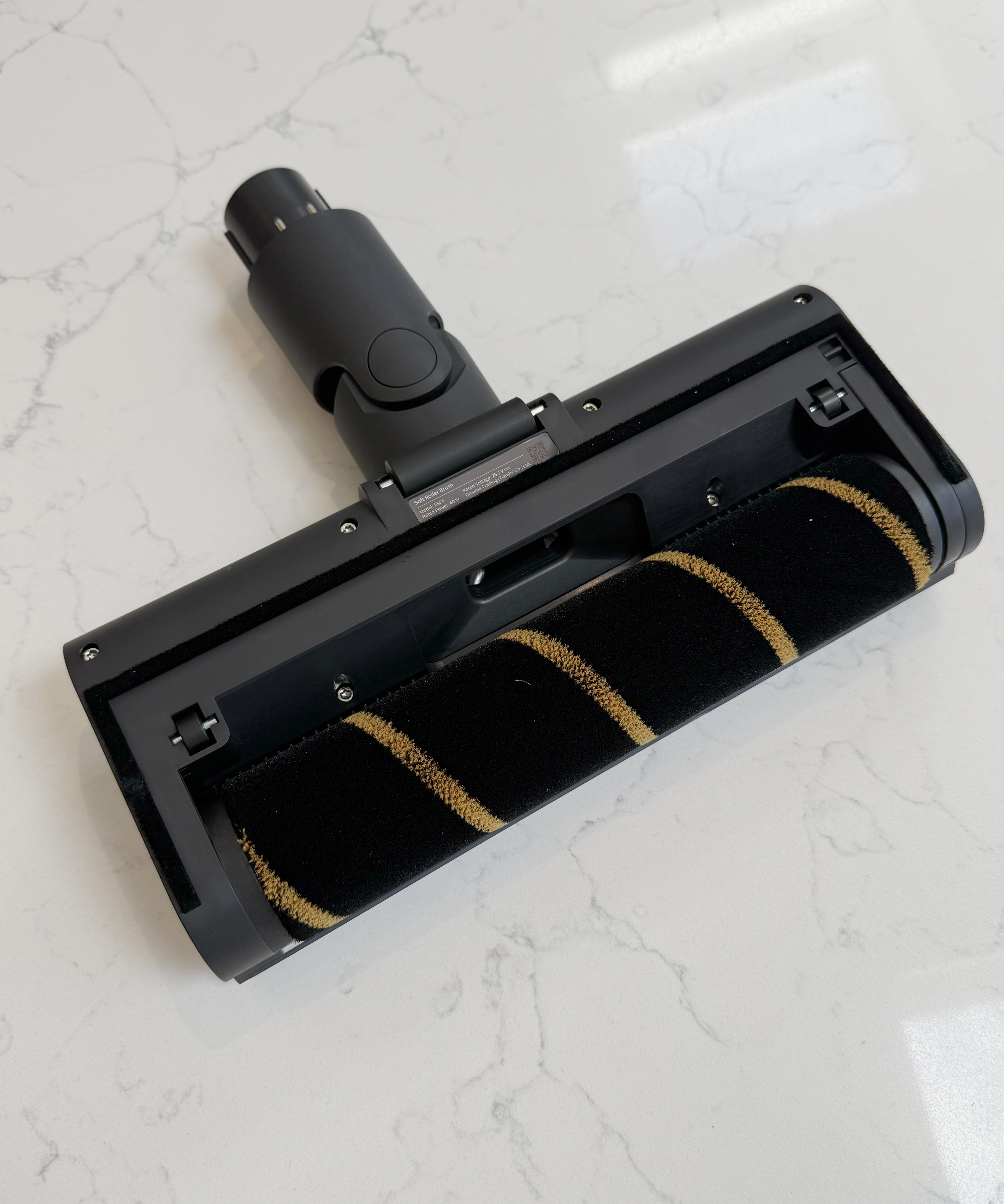 Dreame R10 Pro carpet floorhead underside with black and gold brush roller on a kitchen countertop