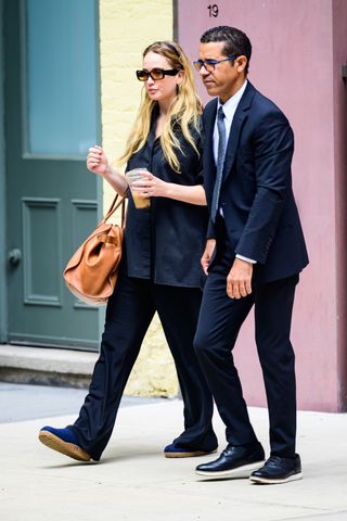 Actress Jennifer Lawrence dons an all-black oversized ensemble and blue flats as she exits her NYC building drinking an iced coffee ahead of a busy day running errands.