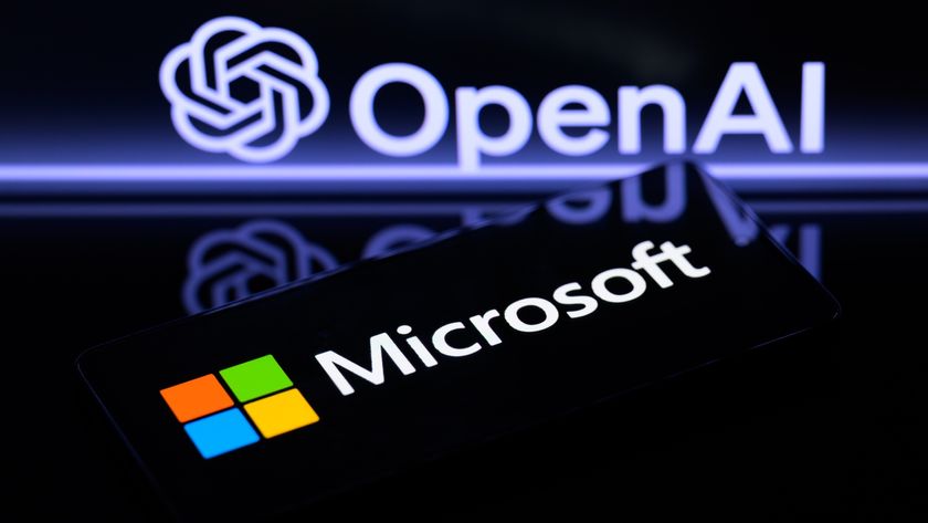 The Microsoft logo is being displayed on a smart phone, with the OpenAI logo visible on the screen in the background.