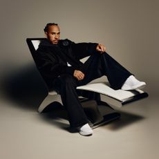 Lewis Hamilton wearing all black and white Lululemon while laying on a chair in a campaign for the fitness brand.