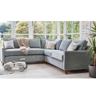 A pale velvet corner sofa bed in a modern living room
