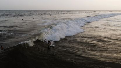 Surfers catch a wave at sunrise off Playa El Zonte in El Salvador