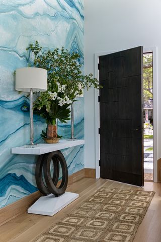 Woven rug in an entryway with blue waved wallpaper