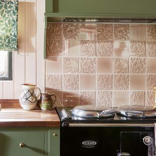 green painted kitchen with pink tile splashback and wooden upstand