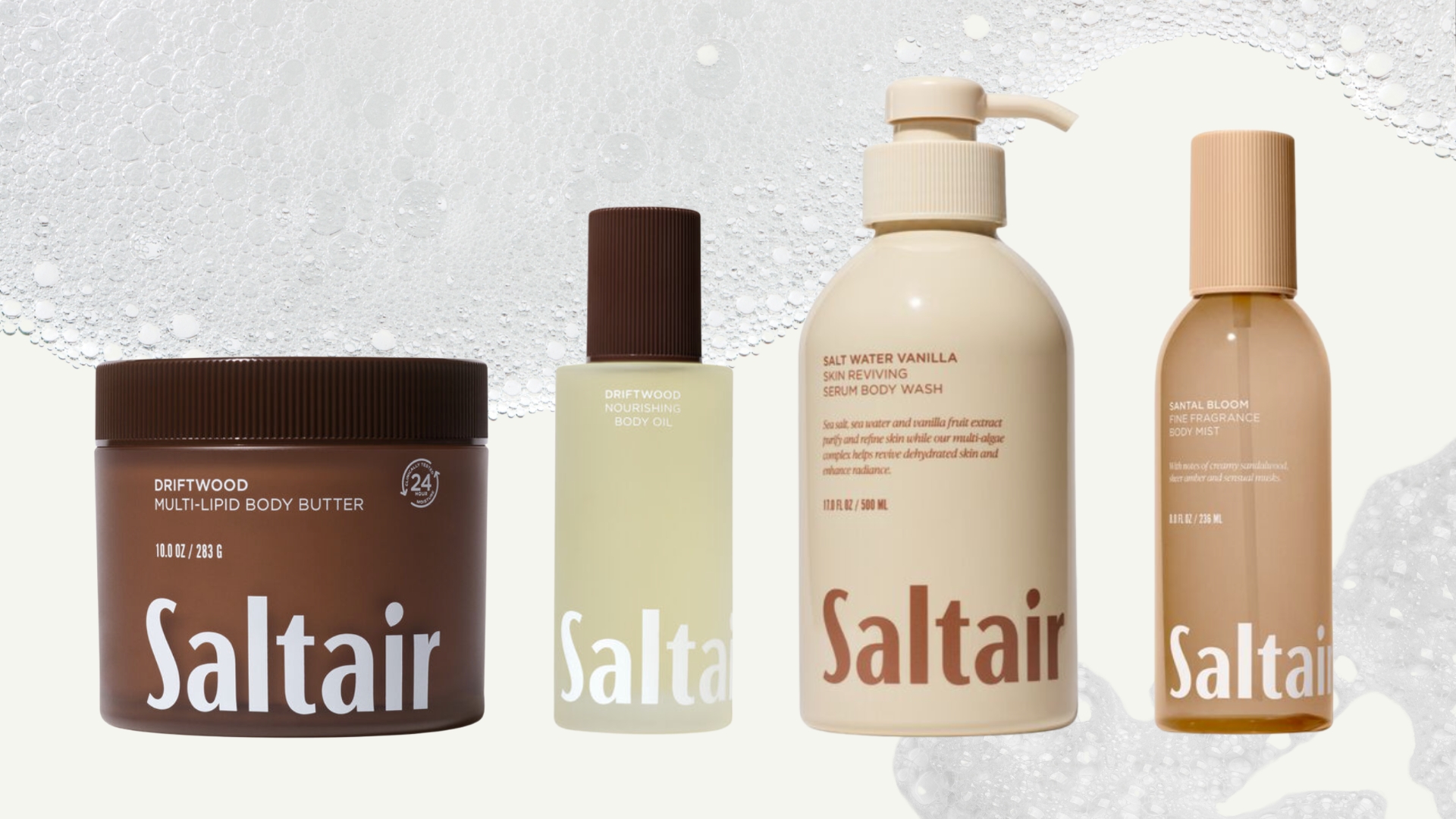 A collage of Saltair bodycare products including the Driftwood multi-lipid body lotion, the Driftwood body oil, the salt water vanilla body wash and Santal Bloom body mist, all arranged in a line across a cream background with a soapy bubble overlay.