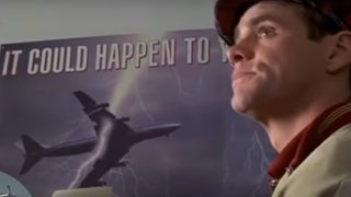 Jim Carrey sits in front of a poster of a plane getting struck by lightning.