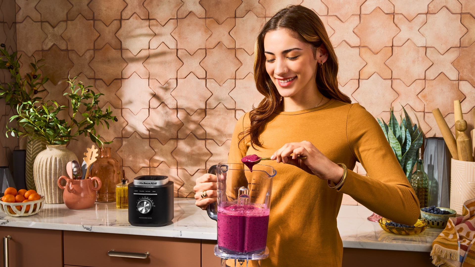 A woman scoops a smoothie inside of the KitchenAid Pure Power Blender