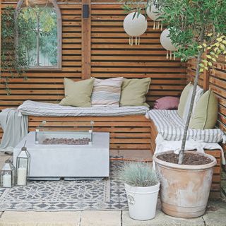 Covered patio area with built-in wooden benches and accessories on the fence and floor