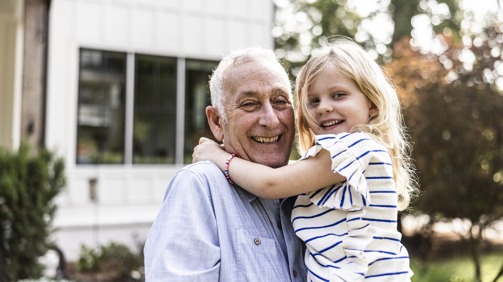 Grandfather and daughter in front of suburban home