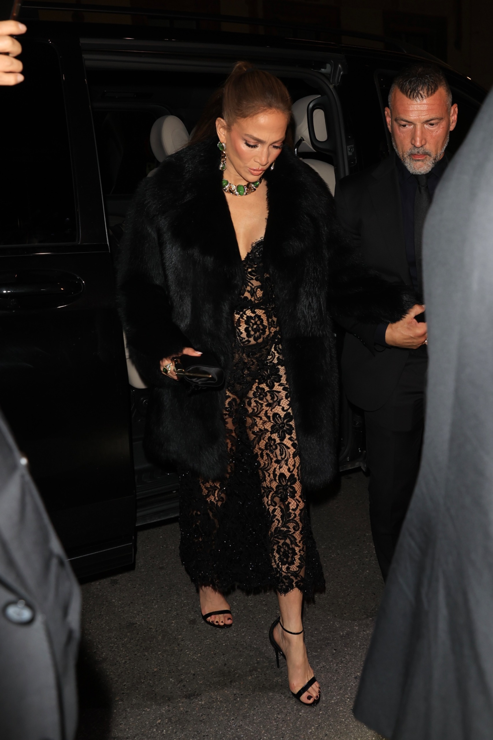 Jennifer Lopez in Milan wearing a black lacy lingerie slip as a naked dress with a fur coat to attend a Dolce and Gabbana party