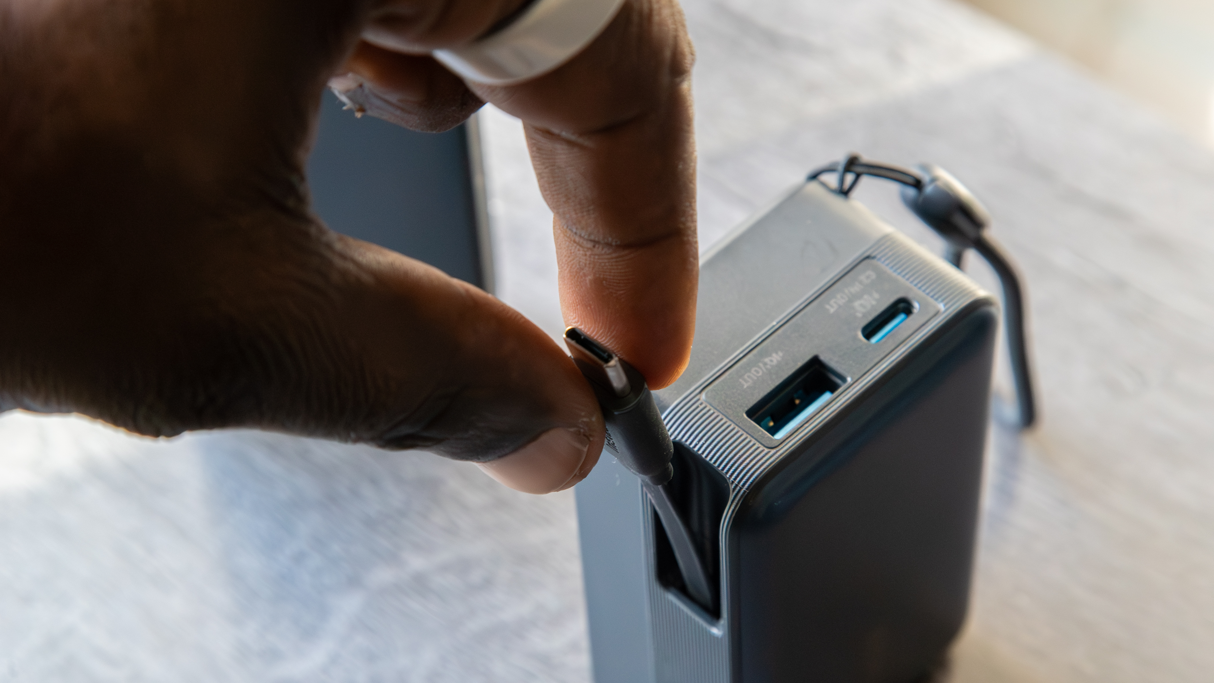 A hand pulling the Anker Nano Power Bank (A1638) retractable USB-C cable