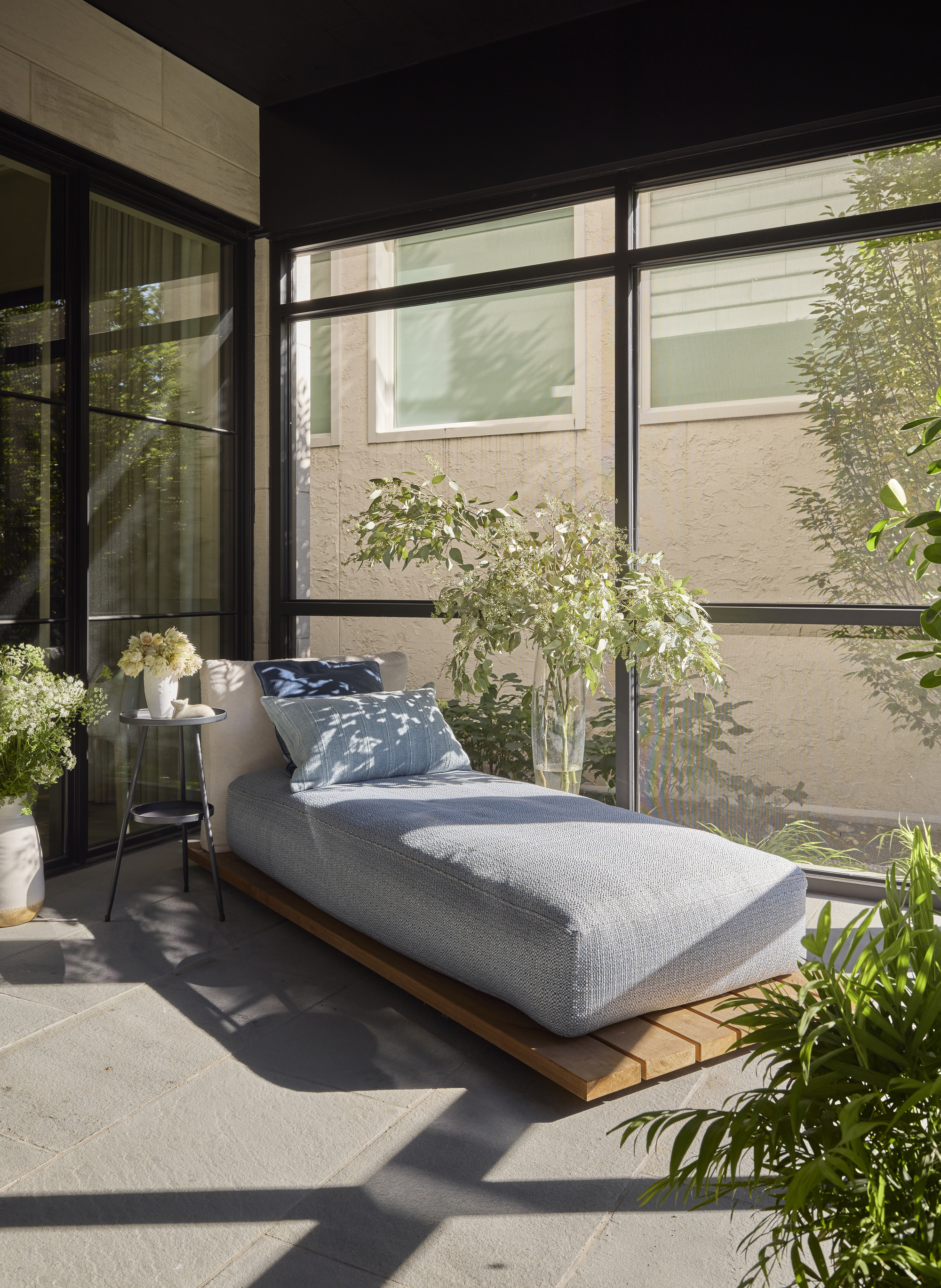 sunroom with lounger, potted plants, big windows, gray floor tiles