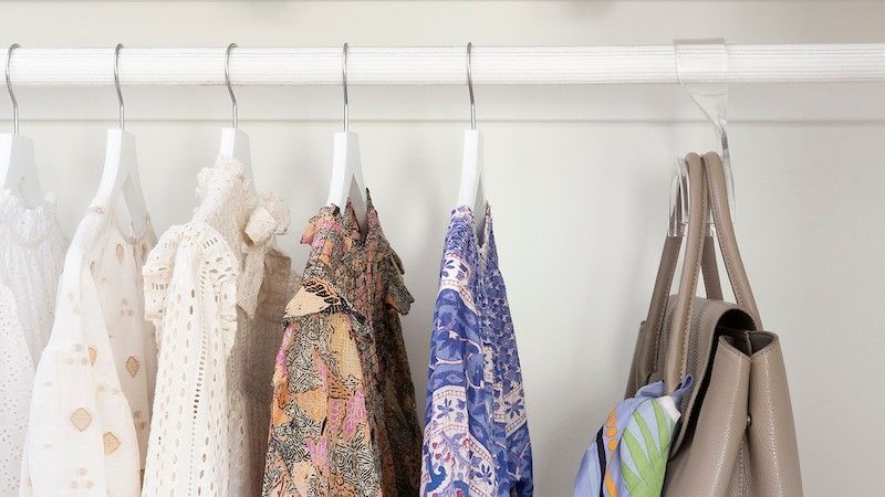 Clean and tidy closet with clothes and purse hanging up