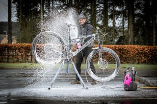 Muc Off pressure washer being used to foam coat a mountain bike for cleaning