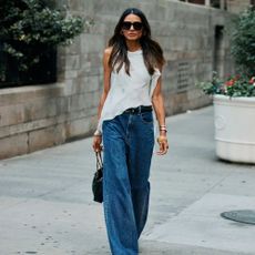 Woman in a white asymmetrical top and wide-leg jeans. 