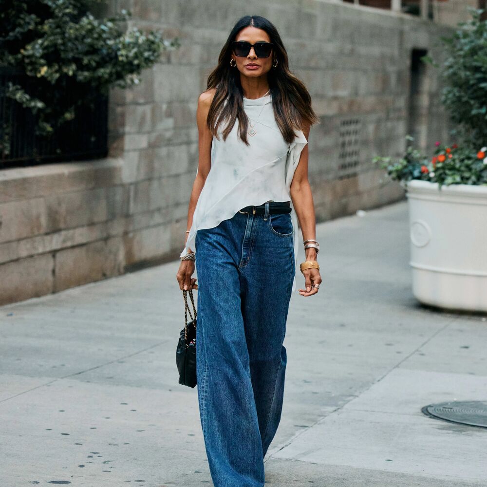 Woman in a white asymmetrical top and wide-leg jeans. 