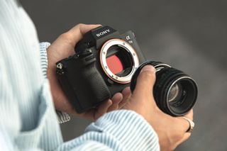 Photographer holding Sony Alpha A7 III and lens
