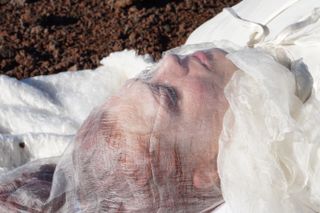J.J. Hastings practices dying on Mars, this up-close shot shows the gauze-y silk piece which covers the face as part of the "Martian death garment" designed by Pia Interlandi.