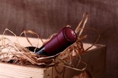 Bottle of red wine in crate with straw