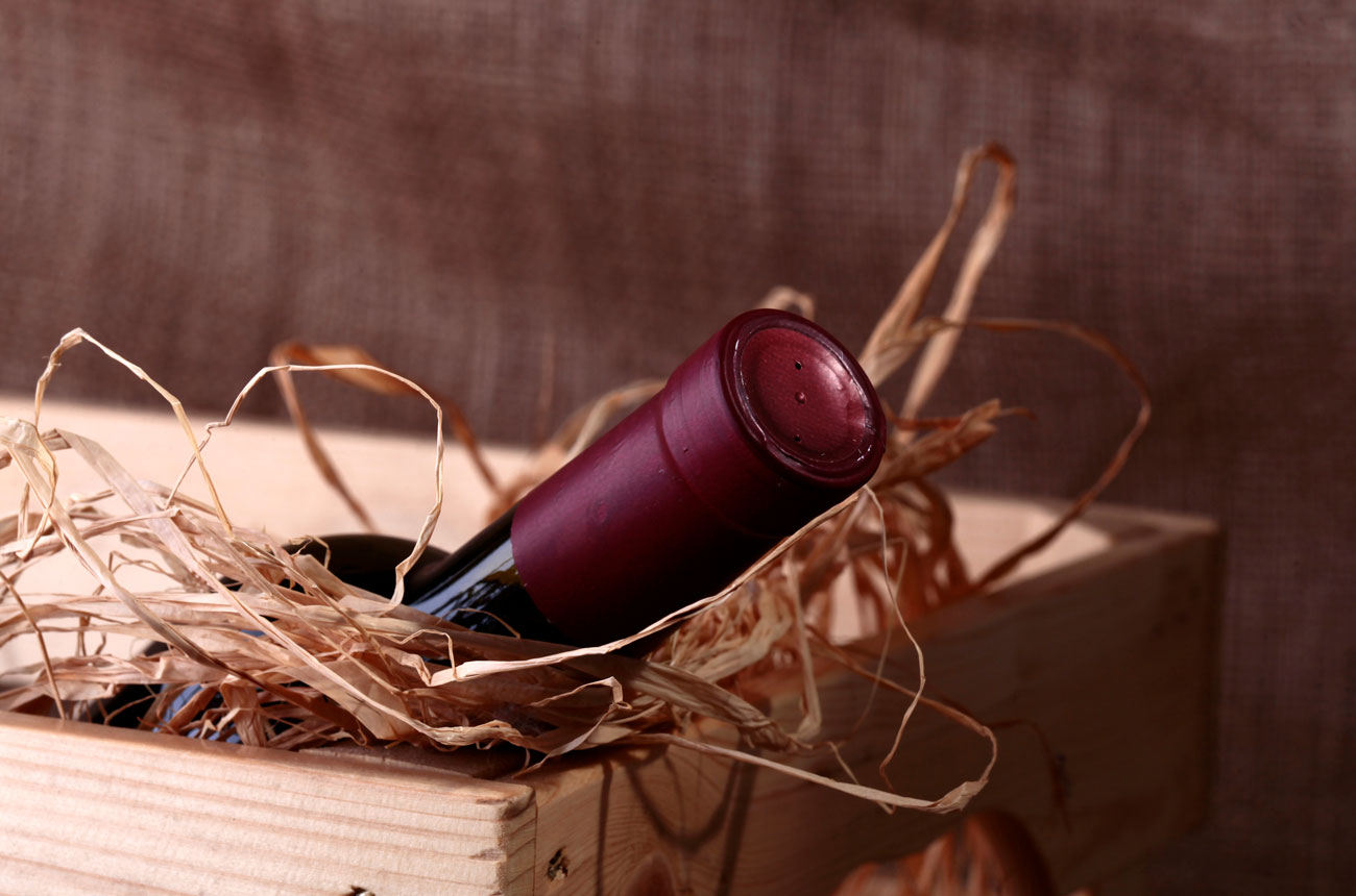 Bottle of red wine in crate with straw