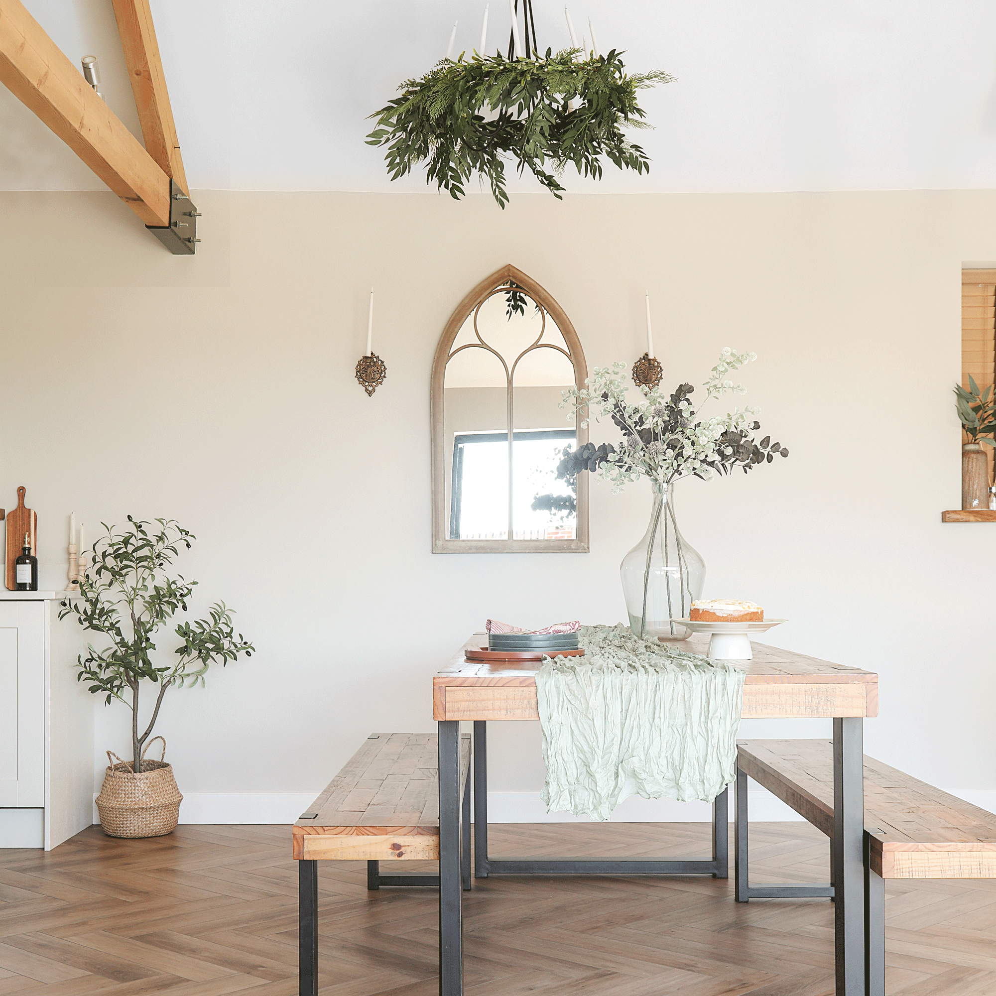 dining area in an open-plan space with vaulted ceilings and a wooden dining table matching benches and a church-style mirror