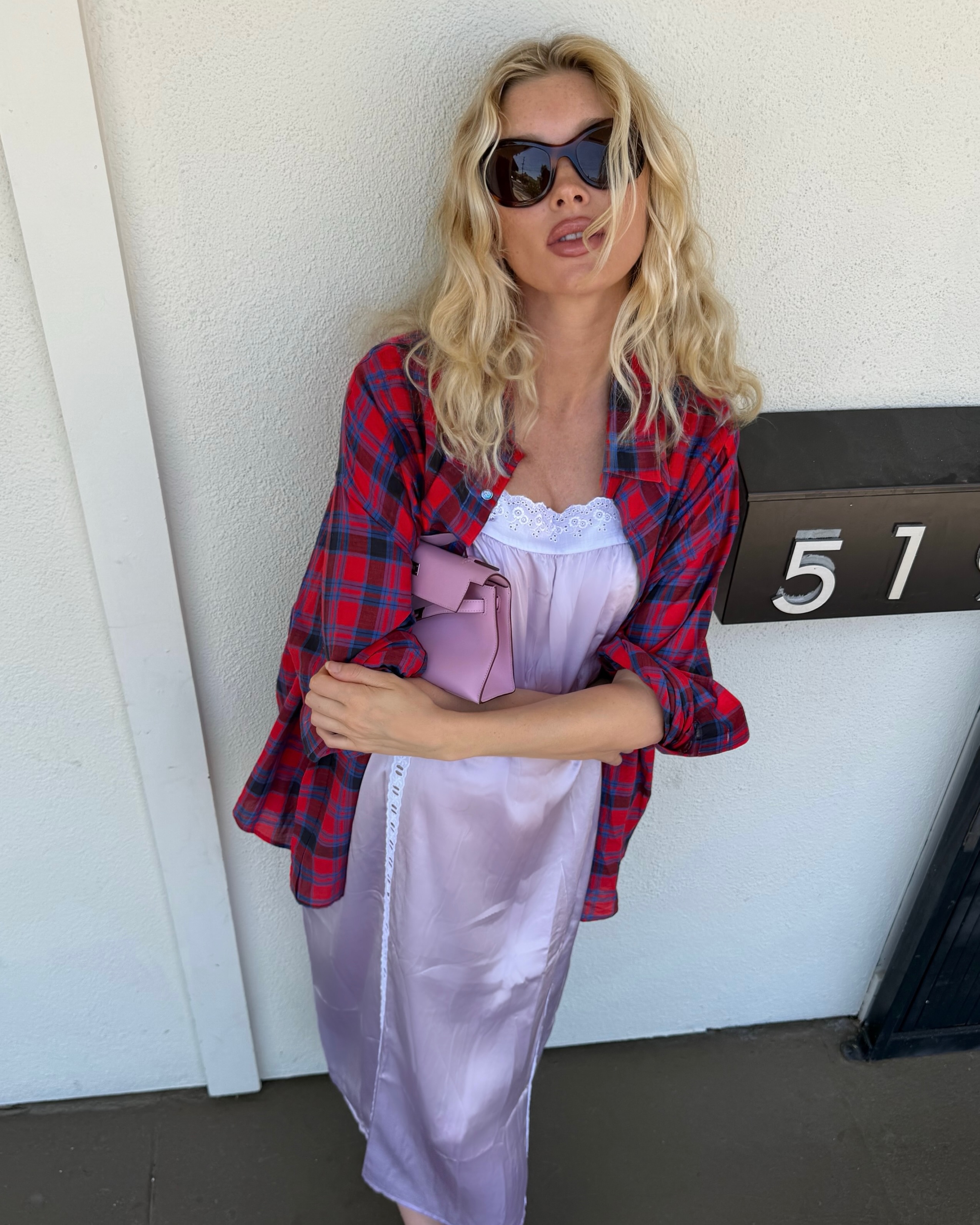 An image of Elsa Hosk wearing a lace-trim satin dress with a checked shirt and pink Hermes Kelly.