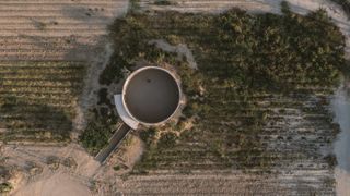 minimalist spiritual enclosure structure in pink hue concrete among desert green nature