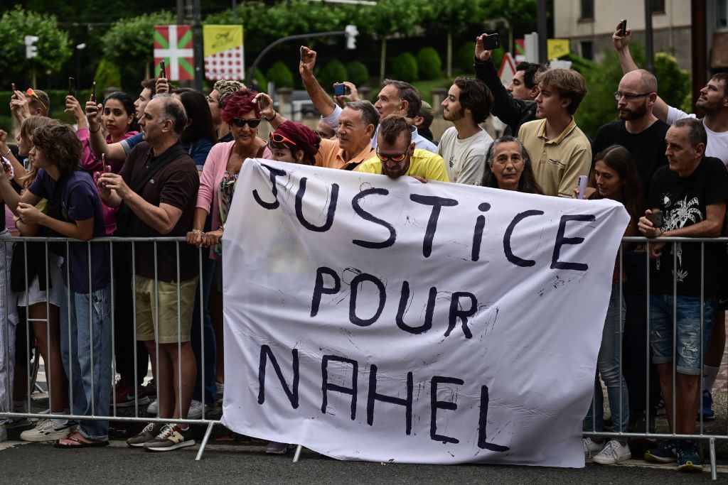 Spectator deploy a banner which reads Justice for Nahel along the race route at the start of the 1st stage of the 110th edition of the Tour de France cycling race 182 km departing and finishing in Bilbao in northern Spain on July 1 2023 Clashes continued across France despite the 45000 police officers deployed the highest number of any night since the start of the protests backed by light armoured vehicles and elite police units Police made more than 1000 arrests and the country braced for more riots ahead of the funeral of the 17yearold teenager who was killed by a police officer during a traffic stop Photo by Marco BERTORELLO AFP Photo by MARCO BERTORELLOAFP via Getty Images