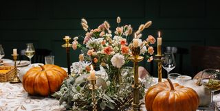A table decorated with pumpkins, flowers, and candles.