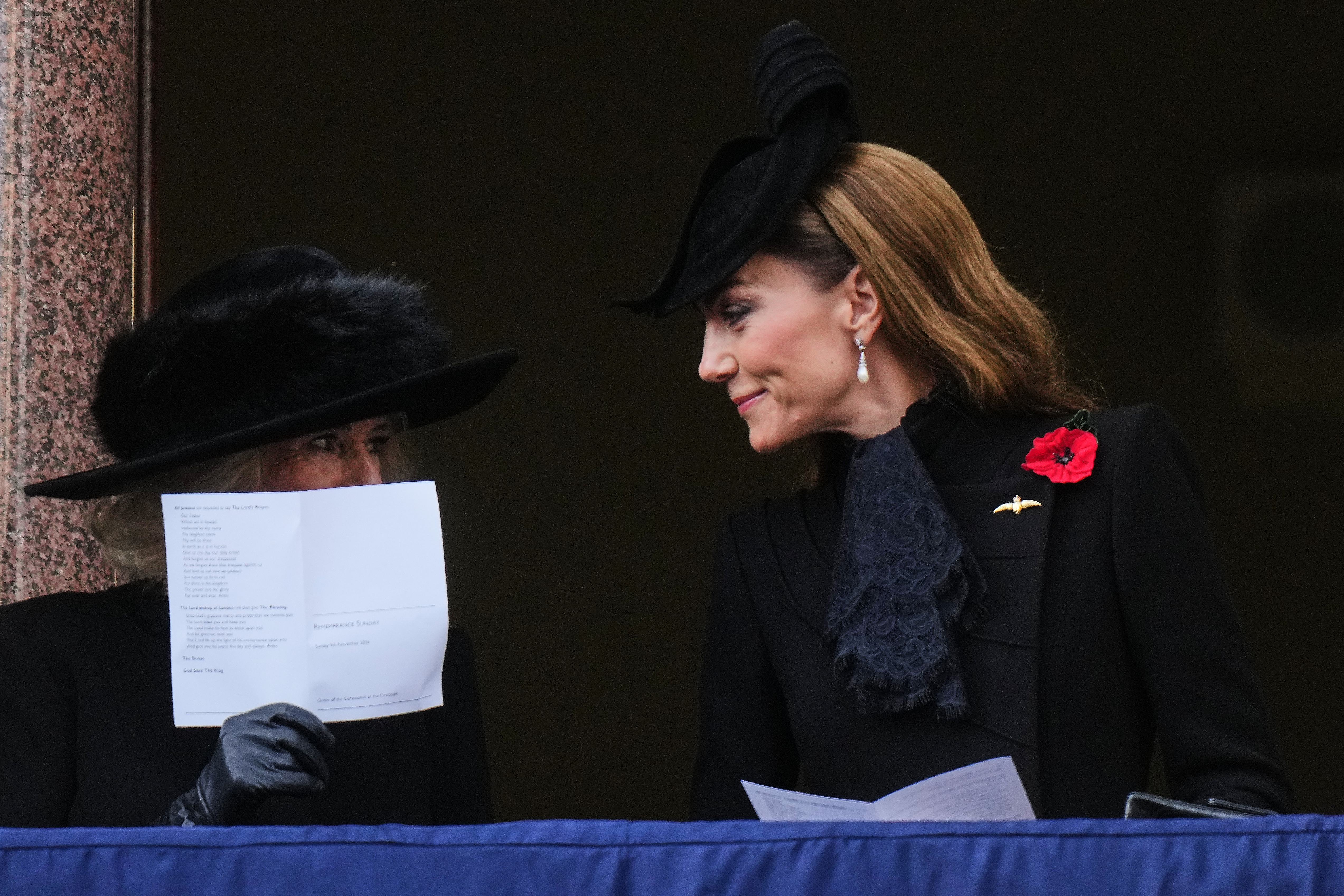 Princess Kate Middleton has long wavy brown hair and wears a black polo neck sweater with a brown blazer