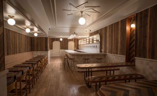 Tørst, Brooklyn, USA. A dining area with a row of tables in an alcove, a bar counter with high chairs and long tables and benches.