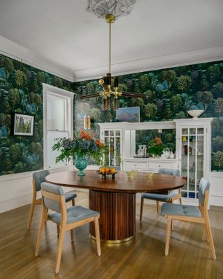 green dining room ideas, green forest wallpaper, walnut oval dining table, grey and wood chairs, white cabinet, retro lighting, wood floor