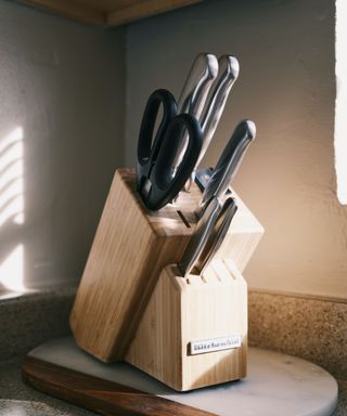 A knife block in partial sun with black handled knives