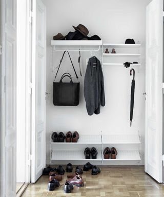 A hallway shoe storage idea with minimal white racks on white wall