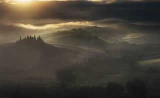 Close to Heaven: Captured in the early hours of the morning, this image showcases the breathtaking beauty of the Tuscan countryside wrapped in a soft veil of mist. Above, the sky is charged with drama as the sun battles to pierce through the dense clouds, casting a golden glow that dances across the landscape. What makes this image unique is the dramatic interplay between light and shadow. The sun, though partially obscured, cast a diffused golden glow that illuminated pockets of the landscape, creating a painterly effect reminiscent of classic Renaissance paintings.