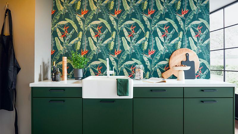 A kitchen with green nature-inspired decor on the cabinets and wallpaper