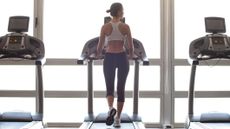 Woman walking on treadmill in a gym in front of window