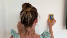 Woman finding a stud in a wall with a stud finder 
