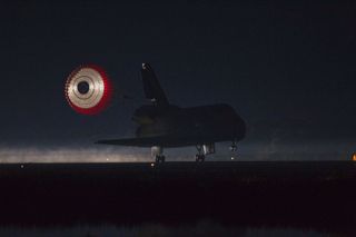 At the Shuttle Landing Facility at NASA's Kennedy Space Center in Florida, the drag chute trailing space shuttle Atlantis is illuminated by the xenon lights on Runway 15 as the shuttle lands for the final time. Securing the space shuttle fleet's place in history, Atlantis marked the 26th nighttime landing of NASA's Space Shuttle Program and the 78th landing at Kennedy.