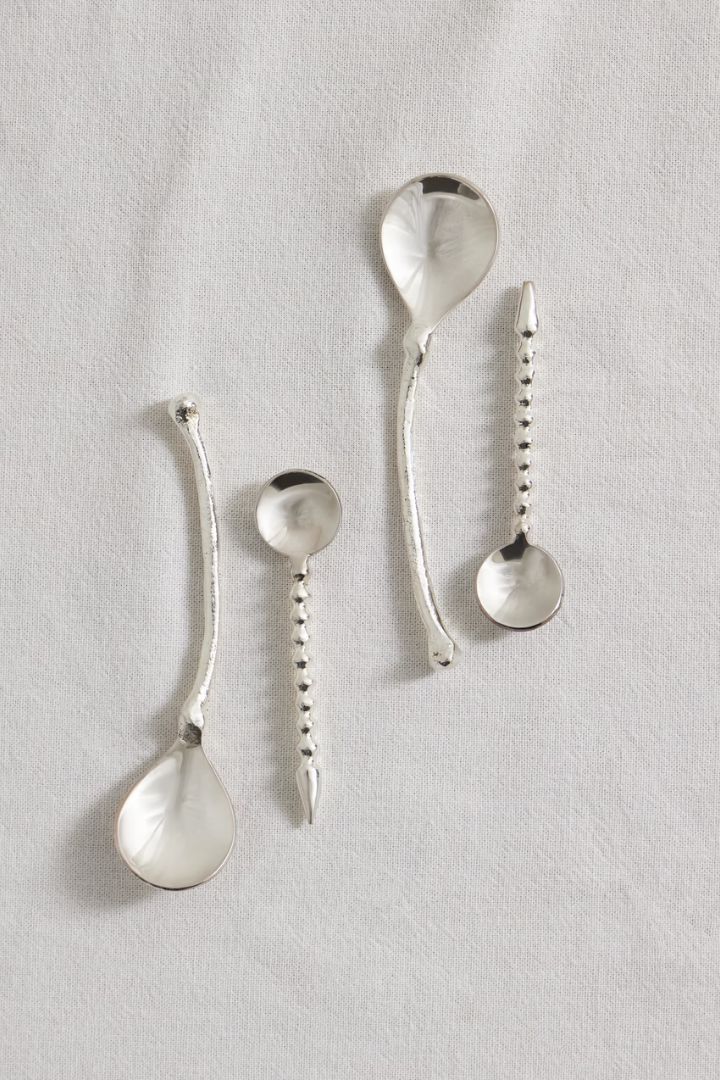 The Totemic Devotion Set of Four Silver-Plated Dessert Spoons against white linen tablecloth.