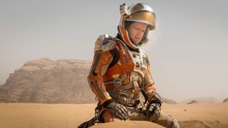 Mark Watney (Matt Damon) in a spacesuit kneeling in the sand on the surface of Mars in &quot;The Martian&quot;